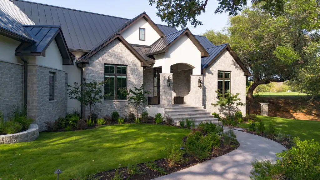 Elegant stone house with a well-maintained garden and curved walkway.