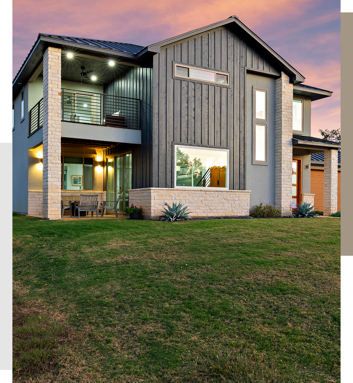 Modern two-story house with large windows and a spacious lawn at sunset.