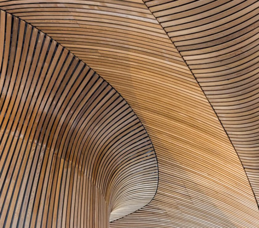 Curved wooden ceiling with parallel slats.