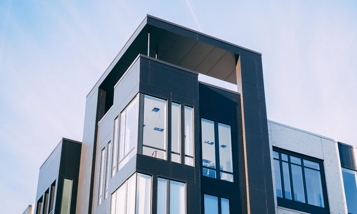 Modern black and white building with large windows and a unique rooftop design.