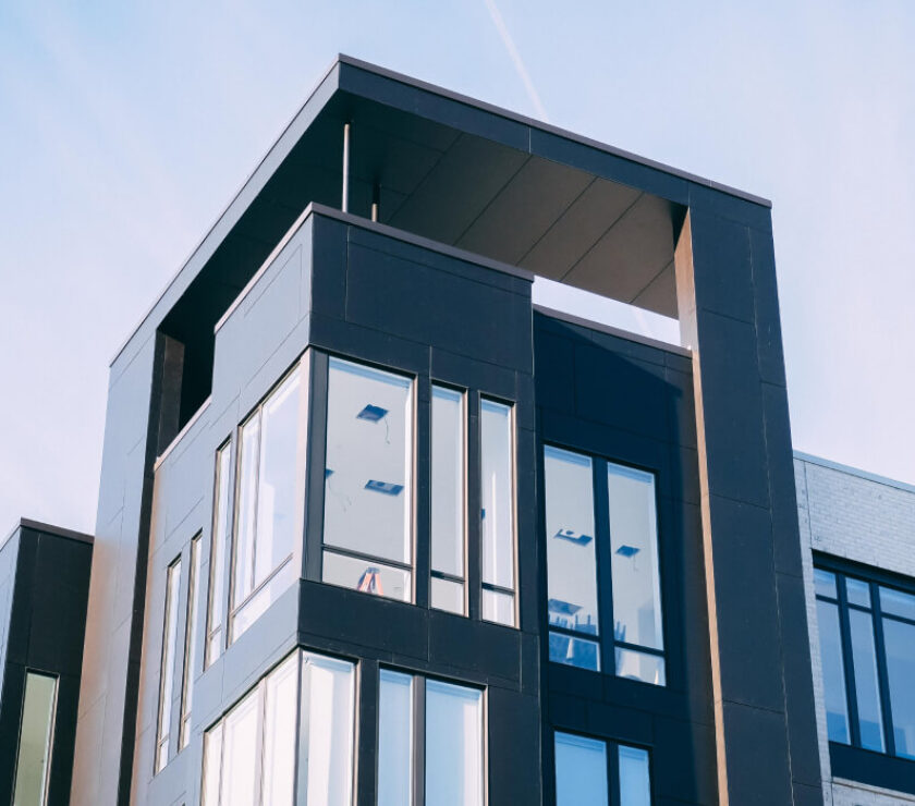 Modern black and white building with large windows and a unique rooftop design.