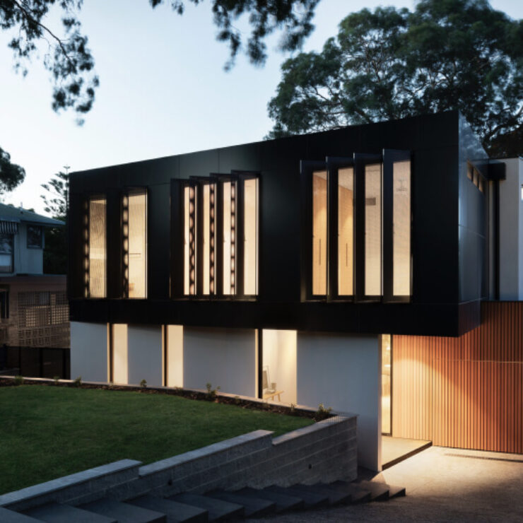 Modern house with large vertical windows illuminated at dusk.