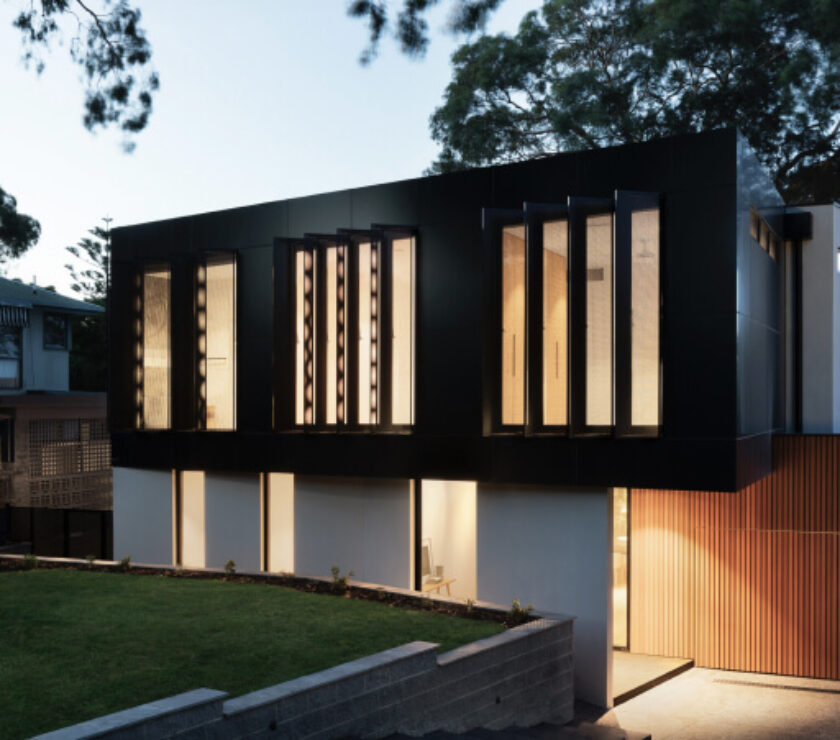 Modern house with large vertical windows illuminated at dusk.