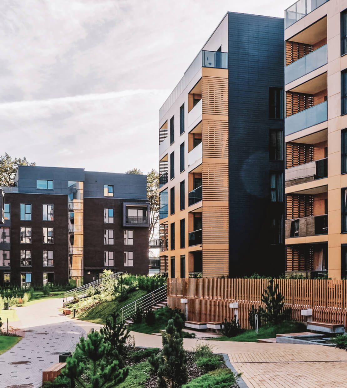 Modern apartment buildings with landscaped courtyard and greenery.