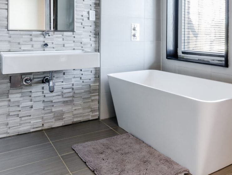 Modern bathroom with a white bathtub and brick wall.
