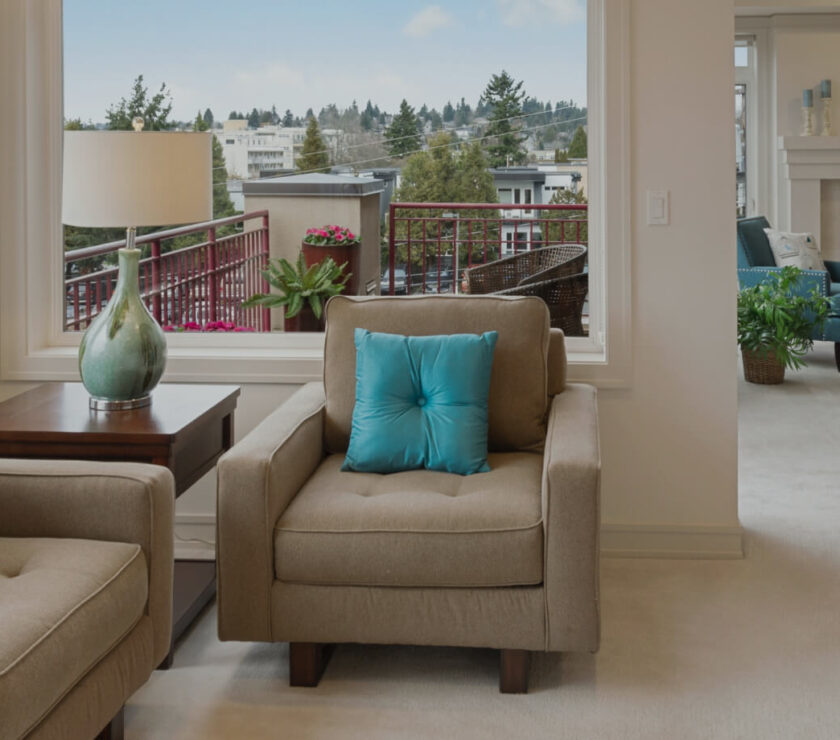 A cozy beige armchair with a teal pillow on a patio.