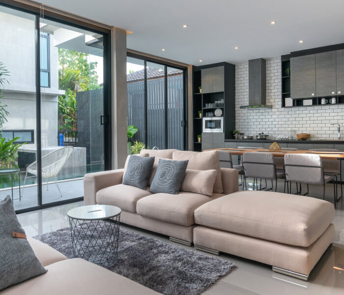 Modern living room with beige sectional sofa and open kitchen.