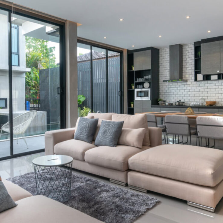 Modern living room with beige sectional sofa and open kitchen.