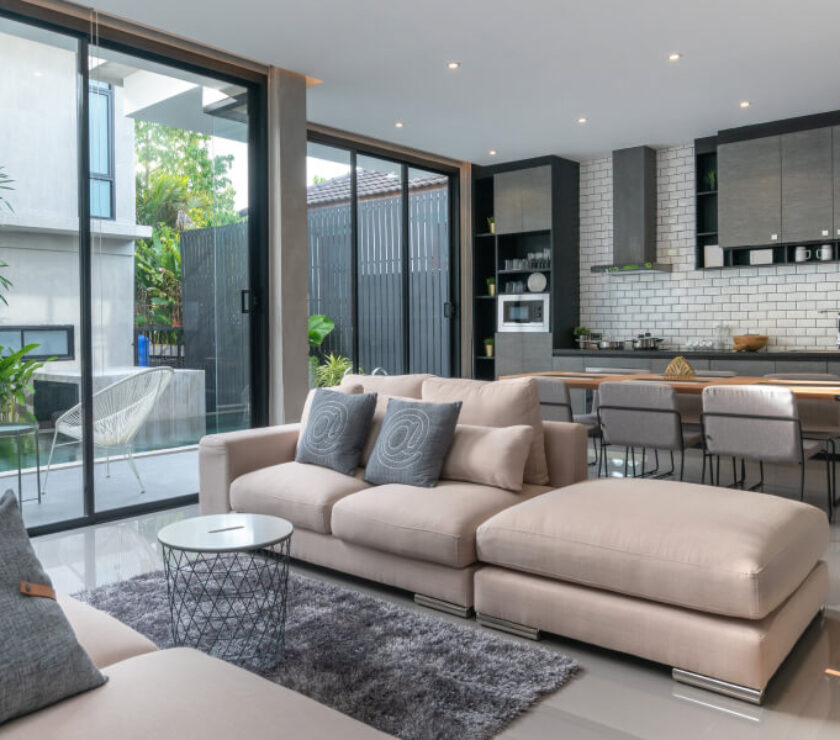 Modern living room with beige sectional sofa and open kitchen.