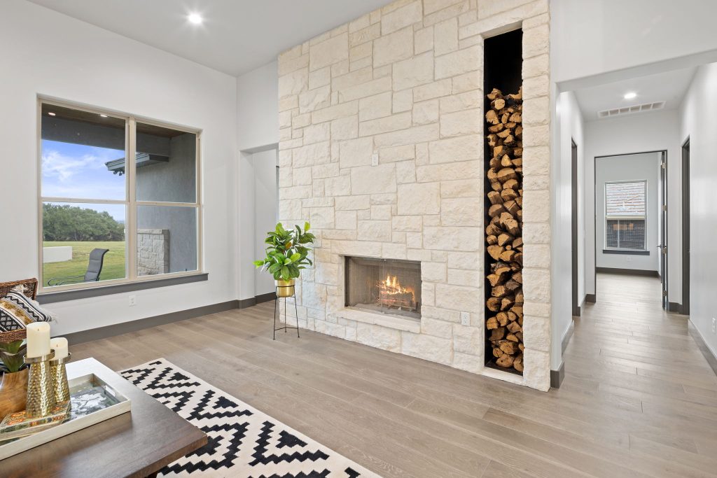 Modern living room with a stone fireplace and wood storage.