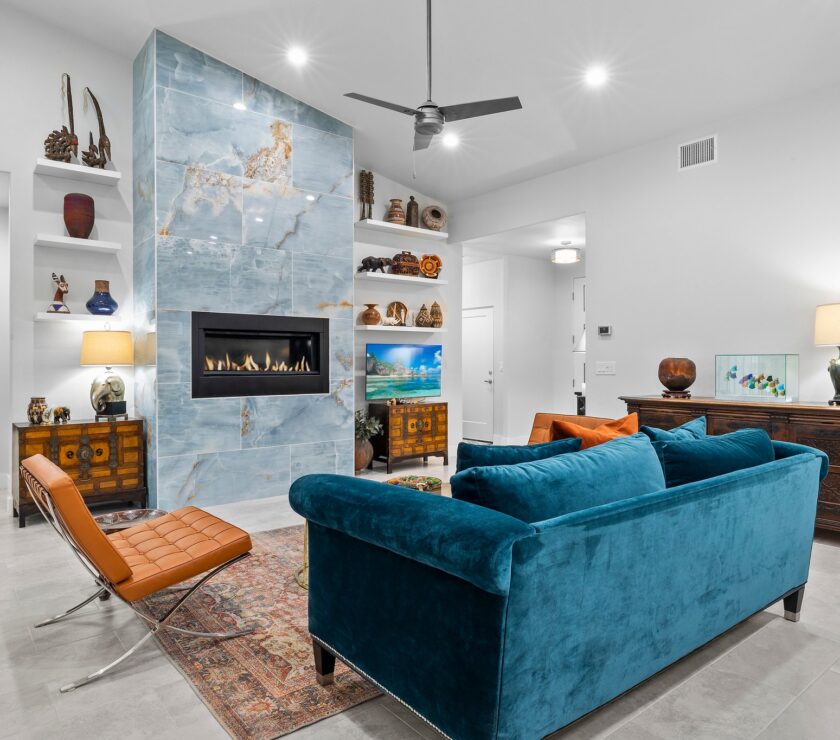 Modern living room with teal sofa and stone fireplace.