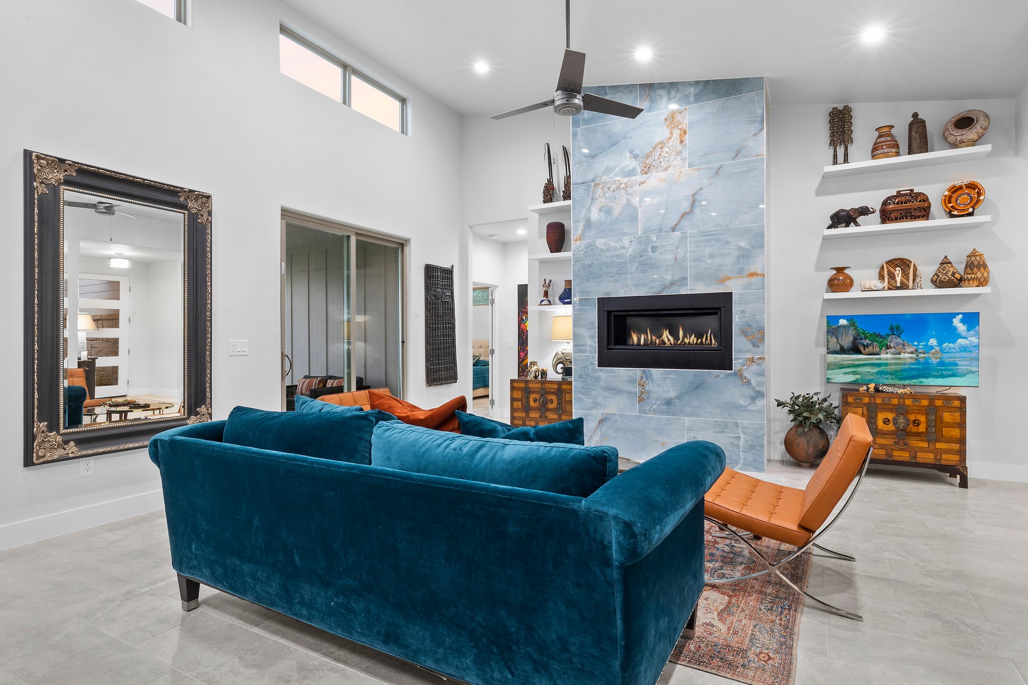 Modern living room with blue velvet sofa and stone fireplace.