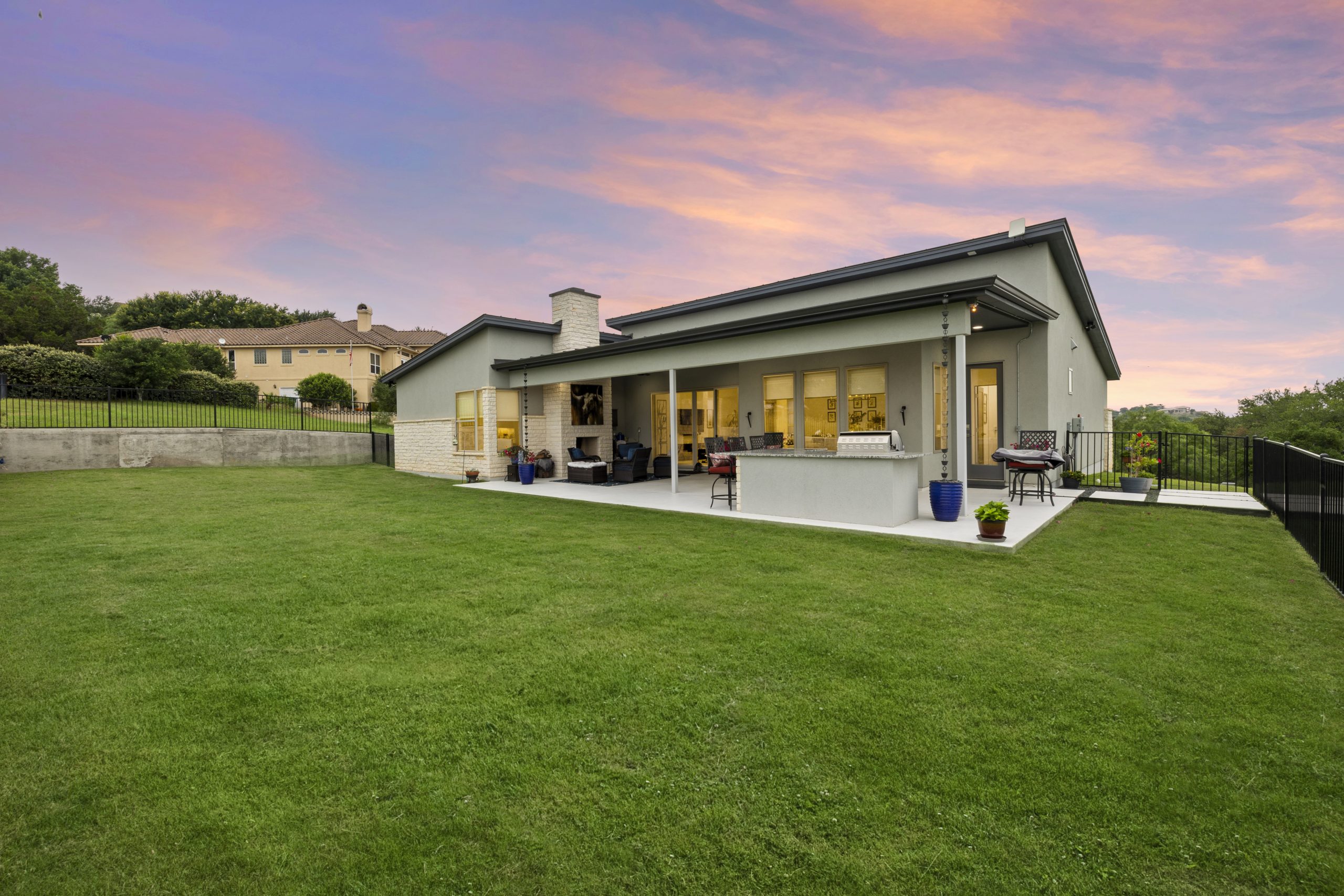 A modern single-story house with a spacious lawn at sunset.
